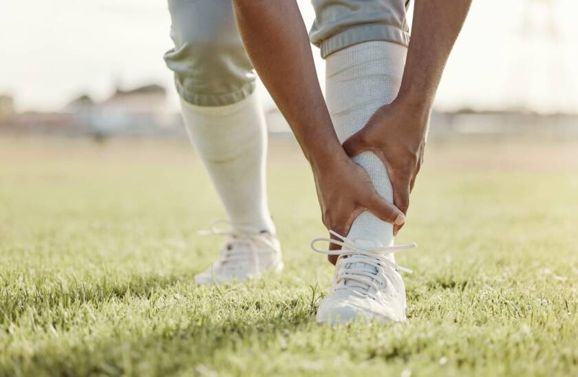 Man holding shin splint pain on sports field